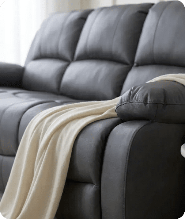 Gray leather sofa with a beige blanket draped over it, set against a neutral background.
