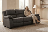 Woman sitting on a gray sofa in a well-lit living room.