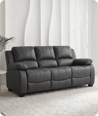 Gray leather sofa in a room with white curtains and a plant.
