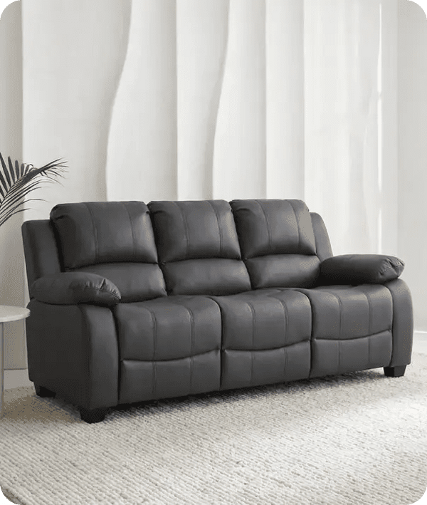 Gray leather sofa in a room with white curtains and a plant.