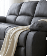 Gray leather sofa with a beige blanket draped over it, set against a neutral background.
