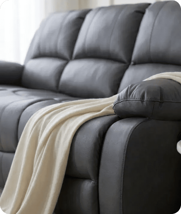 Gray leather sofa with a beige blanket draped over it, set against a neutral background.