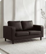 Brown sofa in a room with white walls and a plant.