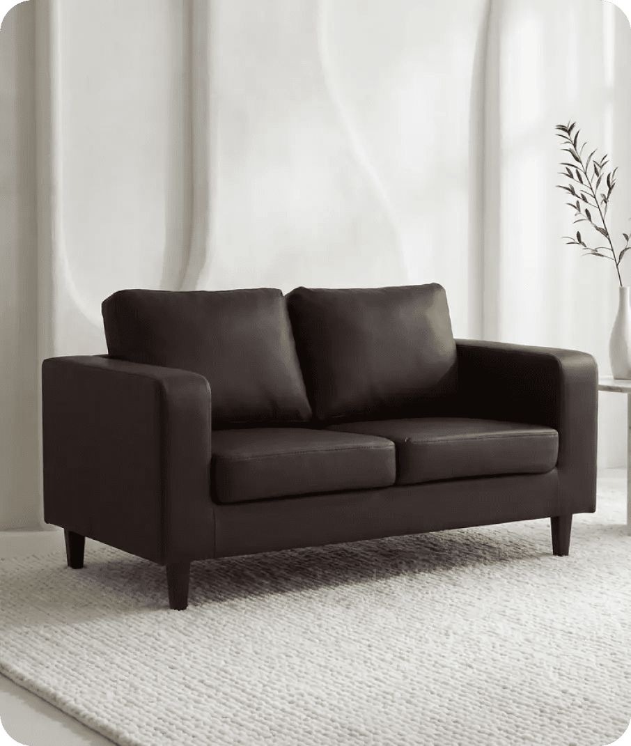Brown sofa in a room with white walls and a plant.