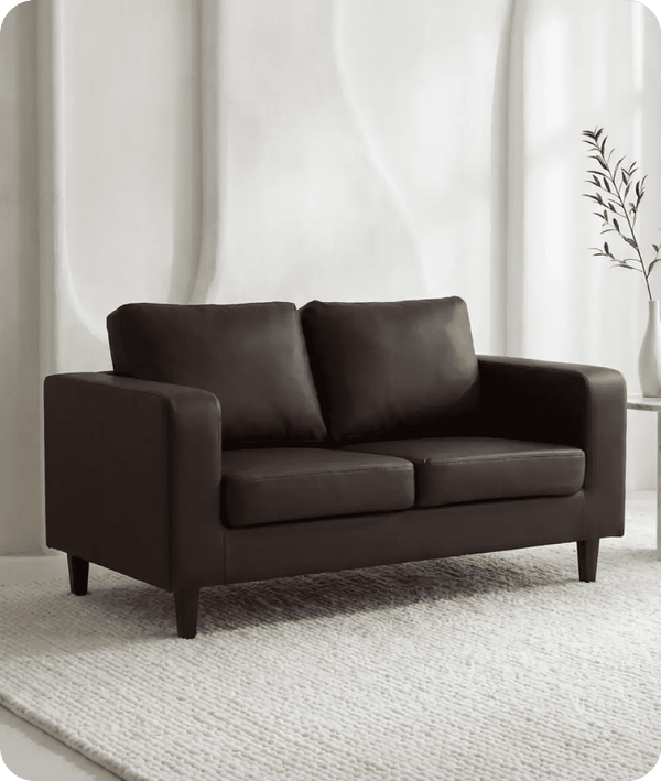 Brown sofa in a room with white walls and a plant.