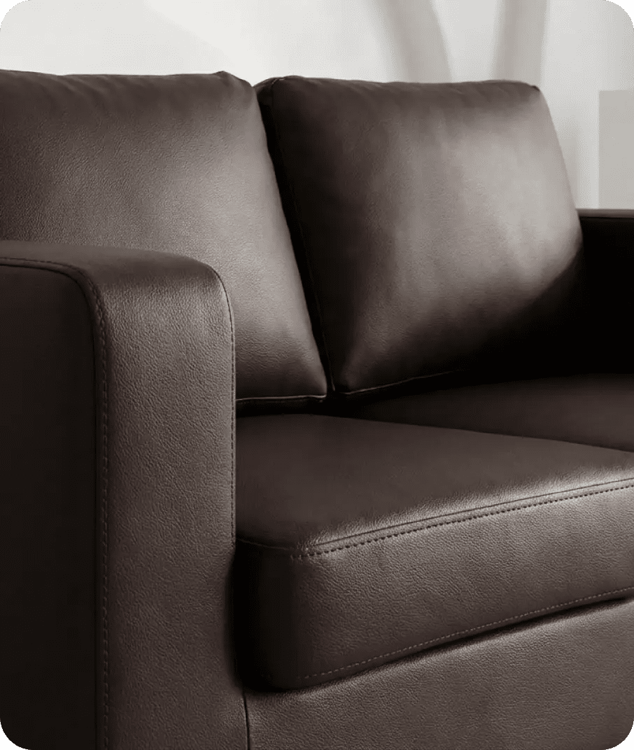 Brown leather sofa with a white curtain in the background