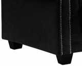 Black upholstered chair with nailhead trim on a white background